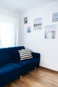 Niebieska sofa w jasnym pomieszczeniu.