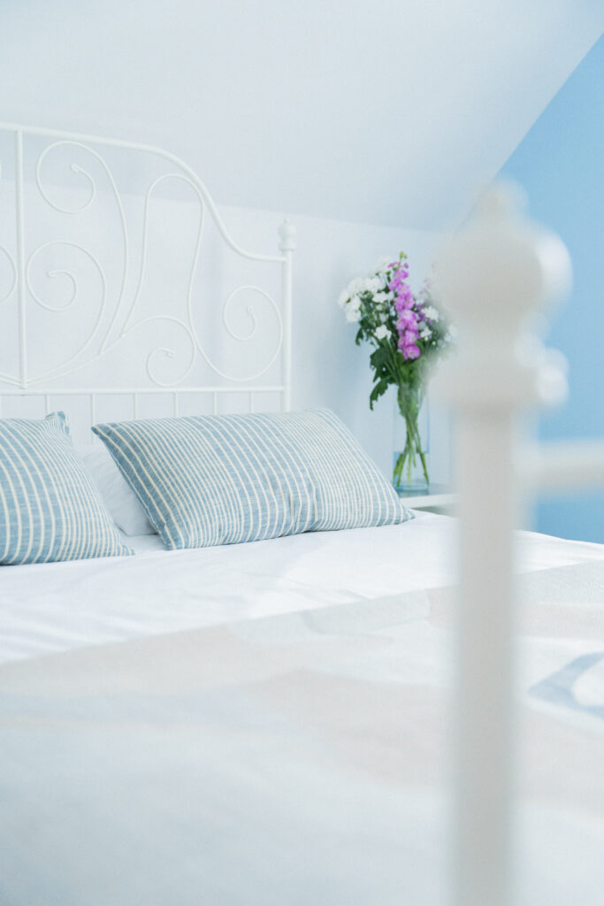 Jasna sypialnia z kwiatami z komfortowym łóżkiem w domkach wierzbówka