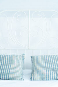 Białe łóżko z niebieskimi poduszkami