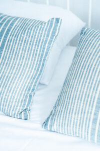 Poduszki w niebieskie paski na łóżku