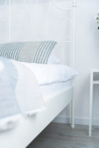 Białe łóżko z niebieską poduszką