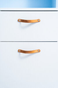 Białe szuflady z brązowymi uchwytami