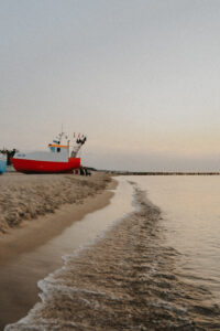 Czerwony kuter na plaży o zmierzchu